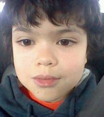 Photo of Julian Pintar. He is a young boy with dark curly hair, olive skin, and large dark brown eyes.