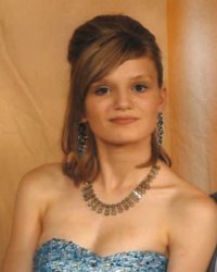 Photo of a teenage girl in a fancy strapless pale blue dress, her hair styled elaborately, wearing sparkling earrings. She has pale skin and brown hair and eyes.